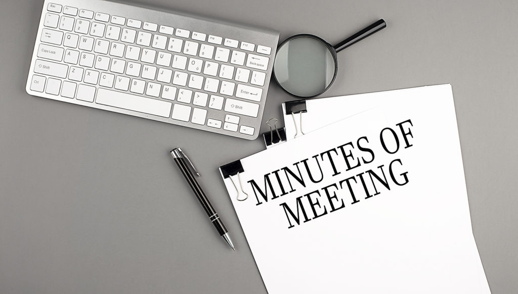 MINUTES OF MEETING text on a paper with keyboard, magnifier and pen. Business concept