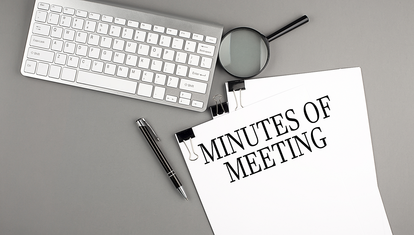 MINUTES OF MEETING text on a paper with keyboard, magnifier and pen. Business concept