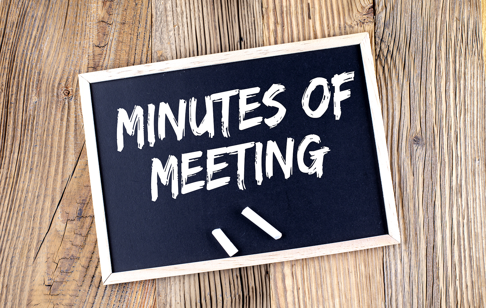 MINUTES OF THE MEETING text on chalkboard on the wooden background